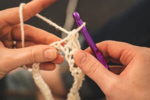 Services Hands crocheting with a purple hook, showcasing intricate yarn details.